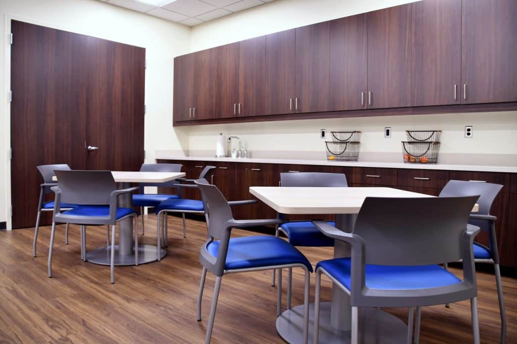 Clean modern lunch room or break room in work place with comfortable seating, tables, refrigerators