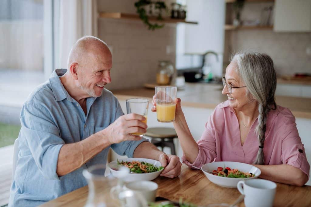 Happy senior couple eating dinner together at home.