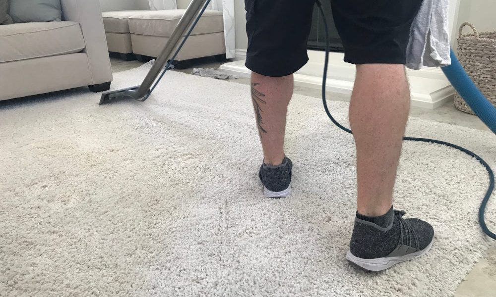 A man is shampooing a white carpet