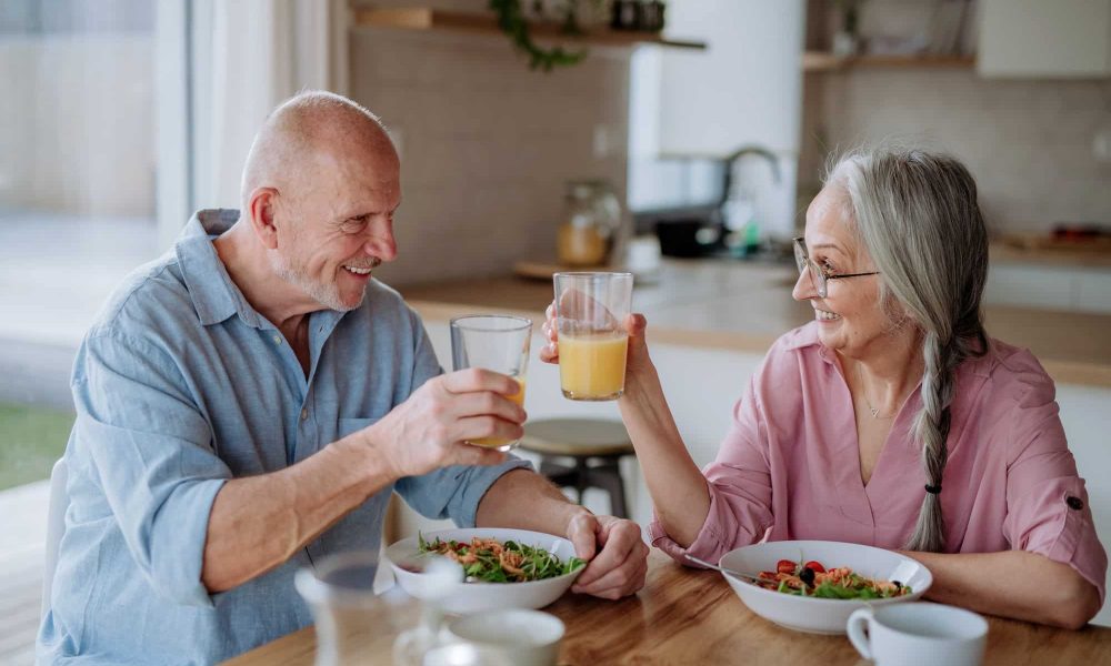 Happy senior couple eating dinner together at home.